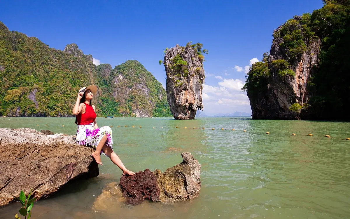 Limestone towers rising straight out of flat water in Phang Nga Bay