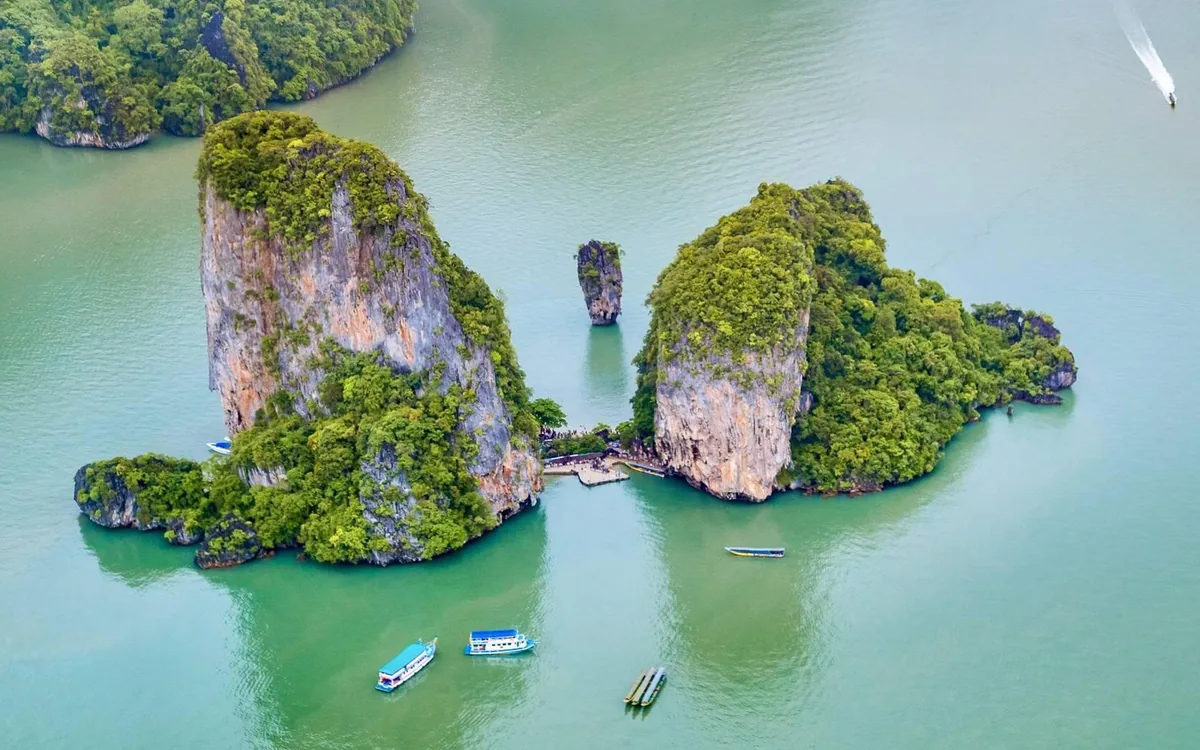 A speedboat at anchor beside a limestone island in Phang Nga Bay